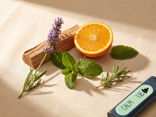 Raw botanicals including lavender, orange, cedarwood and peppermint on cream surface with a Svaroma aromatherapy inhaler